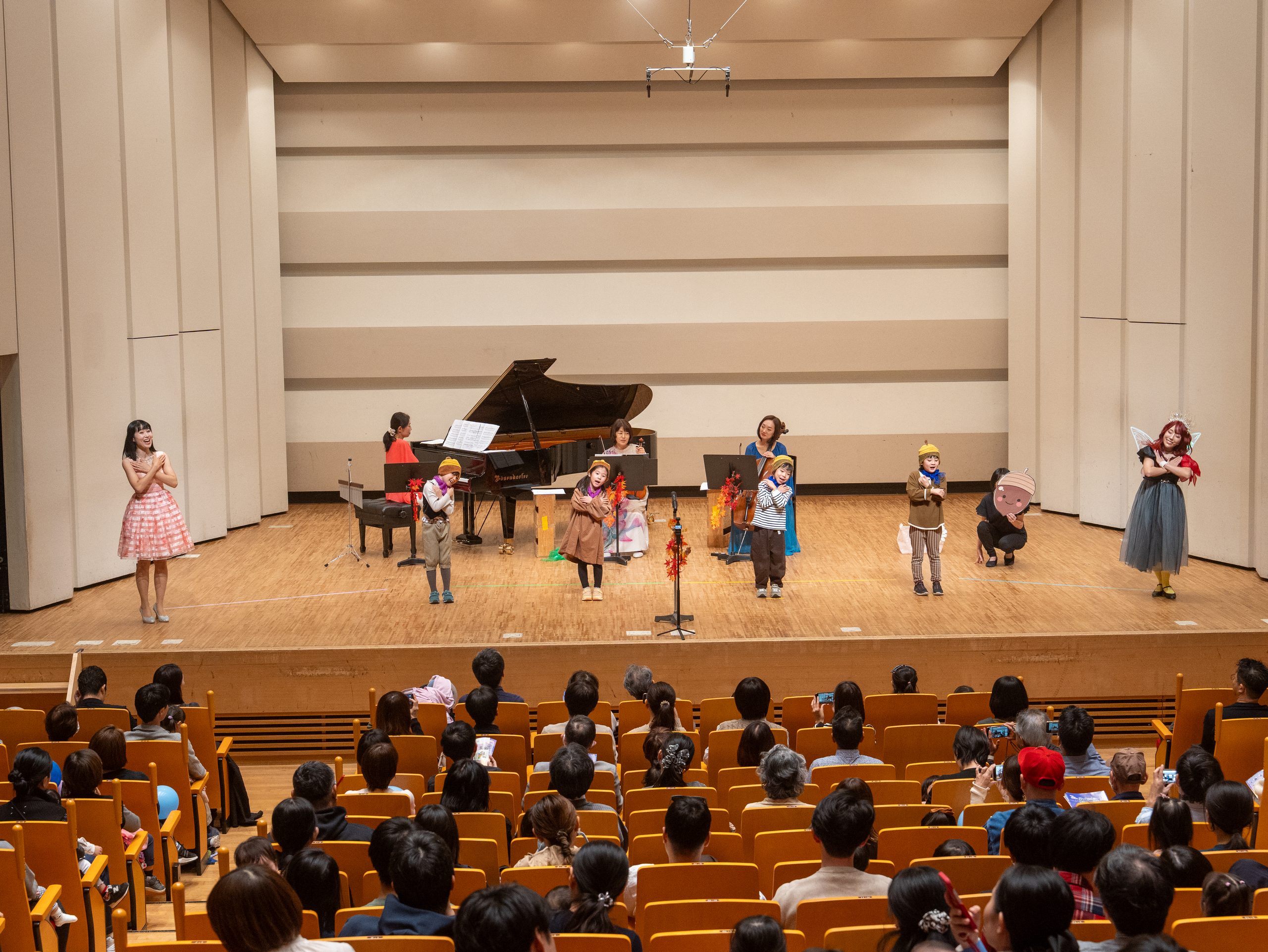 四谷区民ホールの舞台で演じる子どもたちと演奏家、その手前の客席